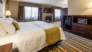 Una habitación de hotel con una cama grande, una chimenea, un televisor y un microondas.