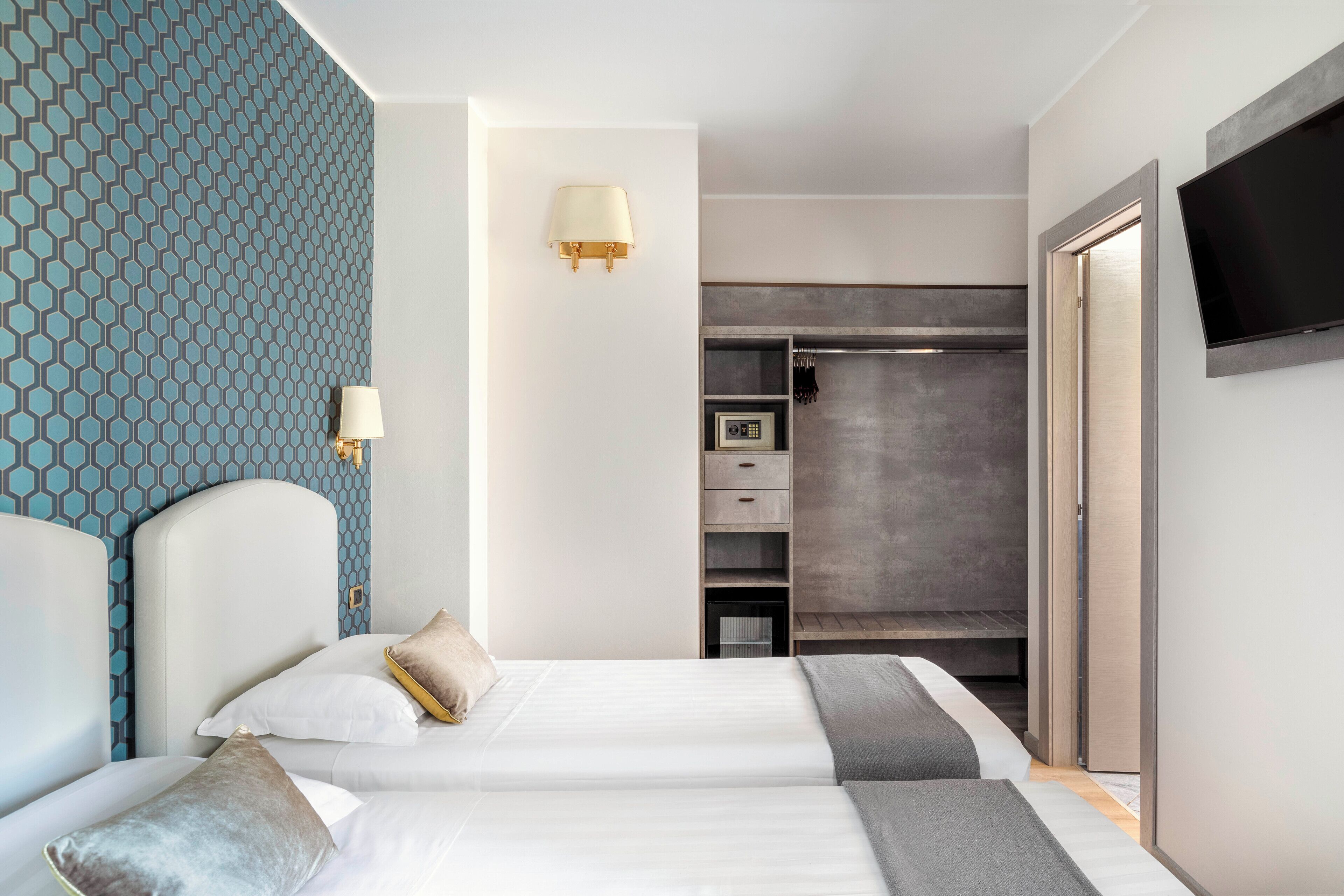 Een moderne hotelkamer met een groot bed, een garderobe, een televisie en een behang met een patroon.