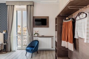 Une chambre d’hôtel moderne dotée d’une grande fenêtre, d’un téléviseur à écran plat, d’un fauteuil bleu, d’une armoire en bois et d’un radiateur.