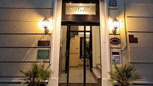 La entrada del Hotel Florence, con un cartel sobre la puerta, una escalera que lleva al interior y dos plantas en macetas a cada lado.