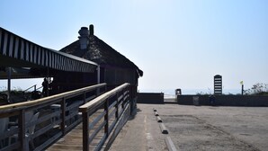 A wooden pier leading to a beachside building with a thatched roof. - Wanna Wanna Inn (South Padre Island)