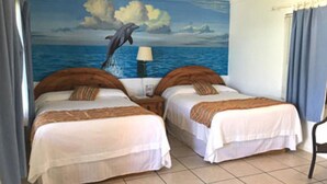 A room with two beds, a mural of a dolphin jumping out of the water, a lamp, and a chair. - Wanna Wanna Inn (South Padre Island)