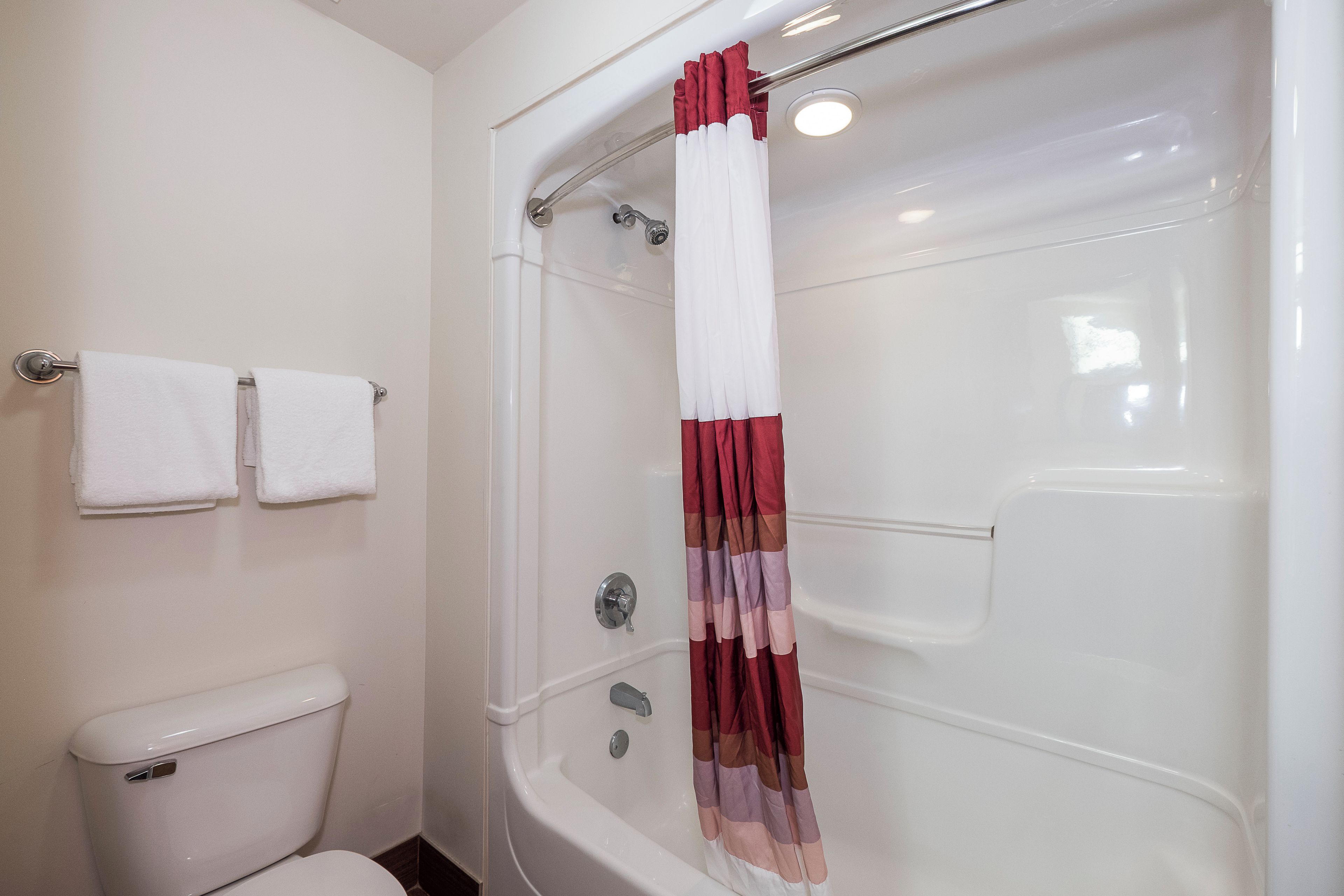 A bathroom with a bathtub, toilet, and two towels on a rack.