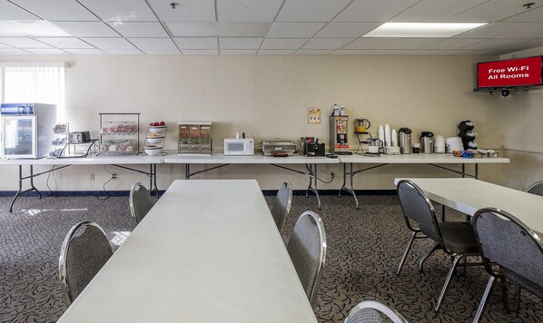 A conference room with a long table, chairs, a microwave, a coffee station, and a TV displaying "Free Wi-Fi All Rooms". - Red Roof Inn Jackson, OH (Jackson)