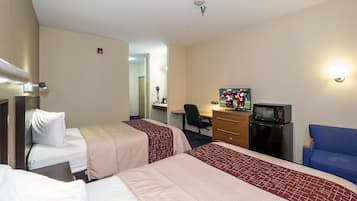 Una habitación de hotel con dos camas, un escritorio con computadora, microondas y televisor.