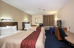 Habitación de hotel con dos camas, un escritorio, una silla, un televisor y un espejo.