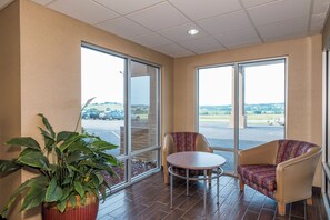 Ein Zimmer mit einem großen Fenster, einem Blumentopf und zwei Stühlen.