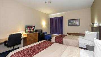 Habitación de hotel con dos camas, un escritorio con computadora, una silla, un televisor y un cuadro en la pared.