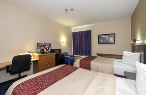 Habitació d'hotel amb dos llits, un escriptori amb un ordinador, una cadira, un televisor i un quadre a la paret.