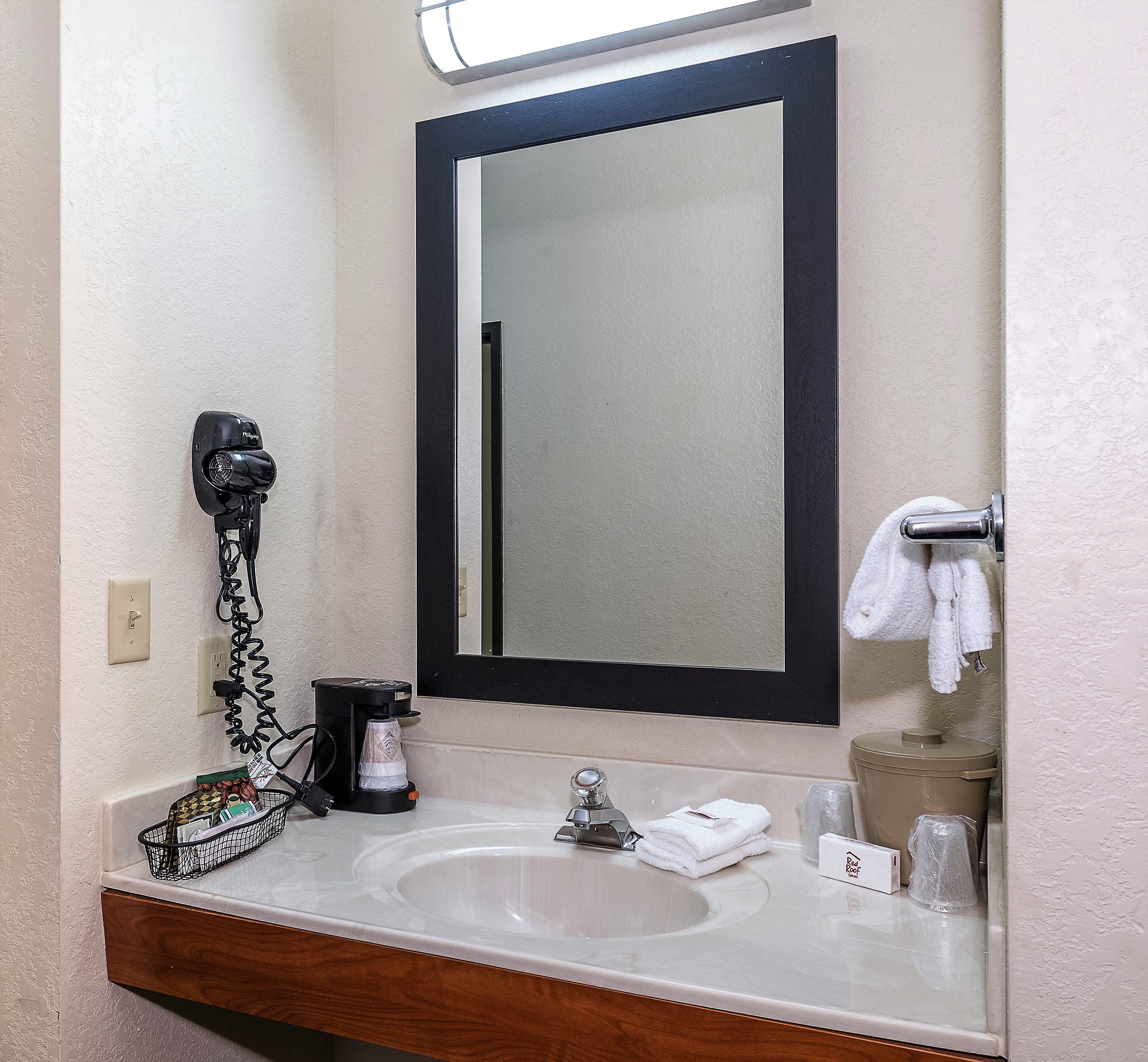 A bathroom with a sink, mirror, towel rack, and a hairdryer.