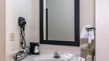 Un baño con lavamanos, espejo, toallero y secador de pelo.