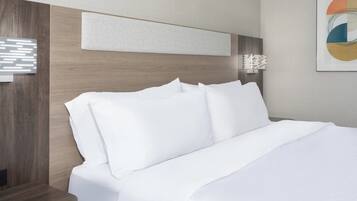 A neatly made bed with white linens in a modern hotel room.