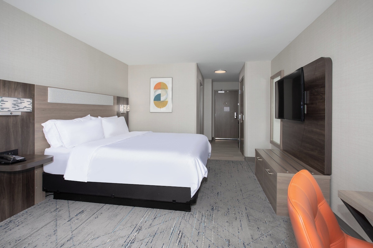 A hotel room with a bed, a TV, a desk, and a chair.