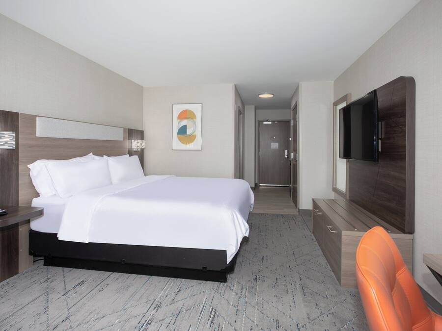 A hotel room with a bed, a desk with a telephone, a TV, and a chair.