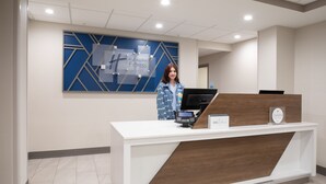 A hotel reception desk with a modern design, a digital kiosk, and a sign indicating the hotel name. - Holiday Inn Express & Suites Grand Junction by IHG (Grand Junction)