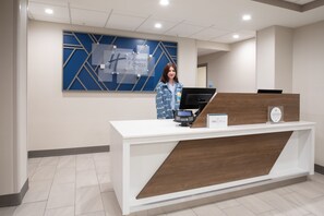 A hotel reception desk with a modern design, a digital kiosk, and a sign indicating the hotel name. - Holiday Inn Express & Suites Grand Junction by IHG (Grand Junction)