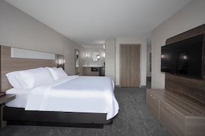 Ein Hotelzimmer mit einem großen Bett, einem Fernseher, einem Schreibtisch mit Spiegel und einem Kleiderschrank.