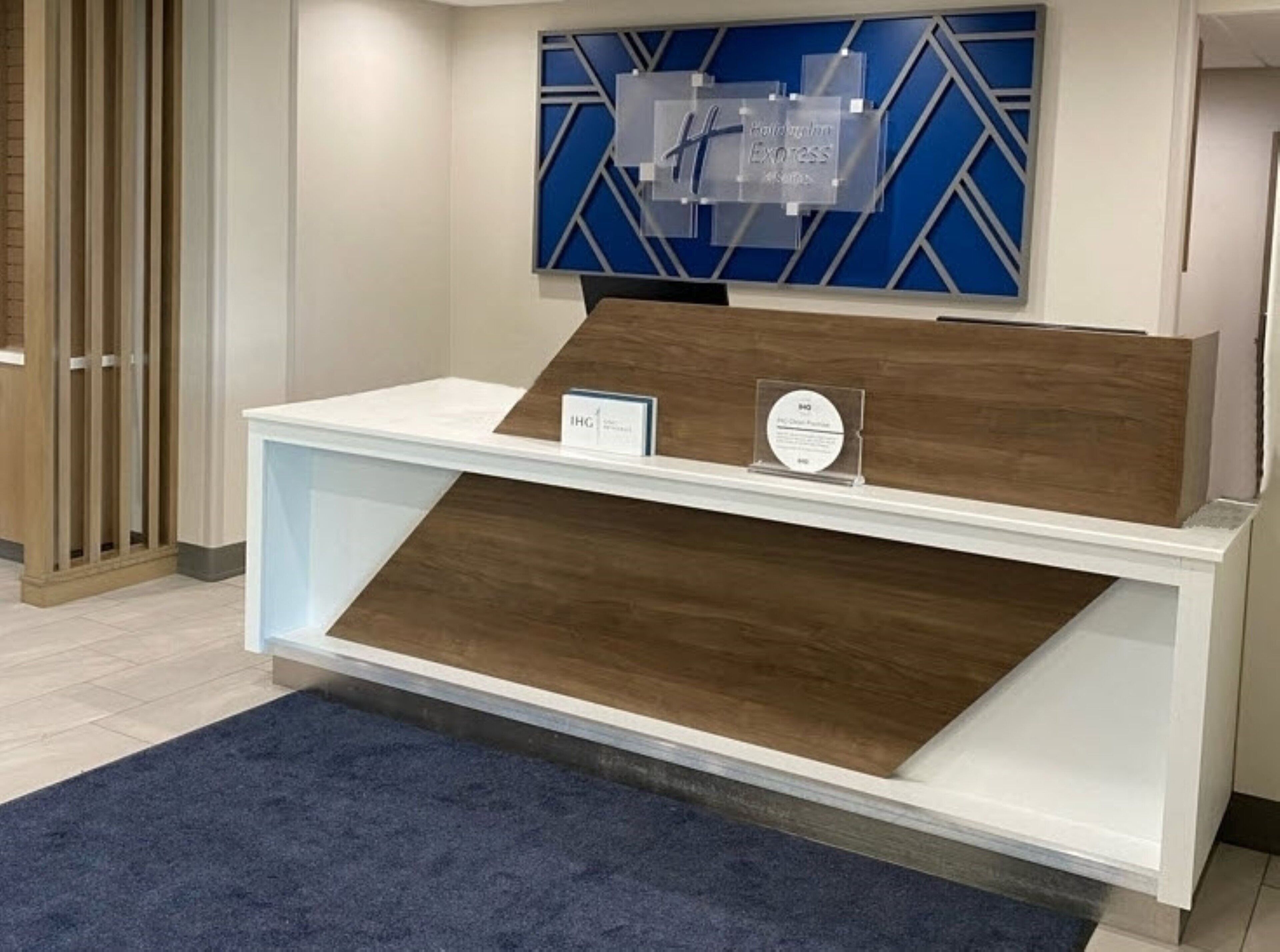 A reception desk with a blue geometric wall design, a wooden counter, and a blue carpet.