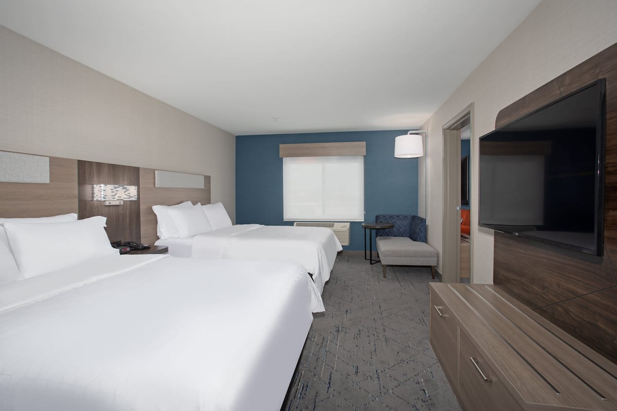 A hotel room with two beds, a television, a small table, and a chair.