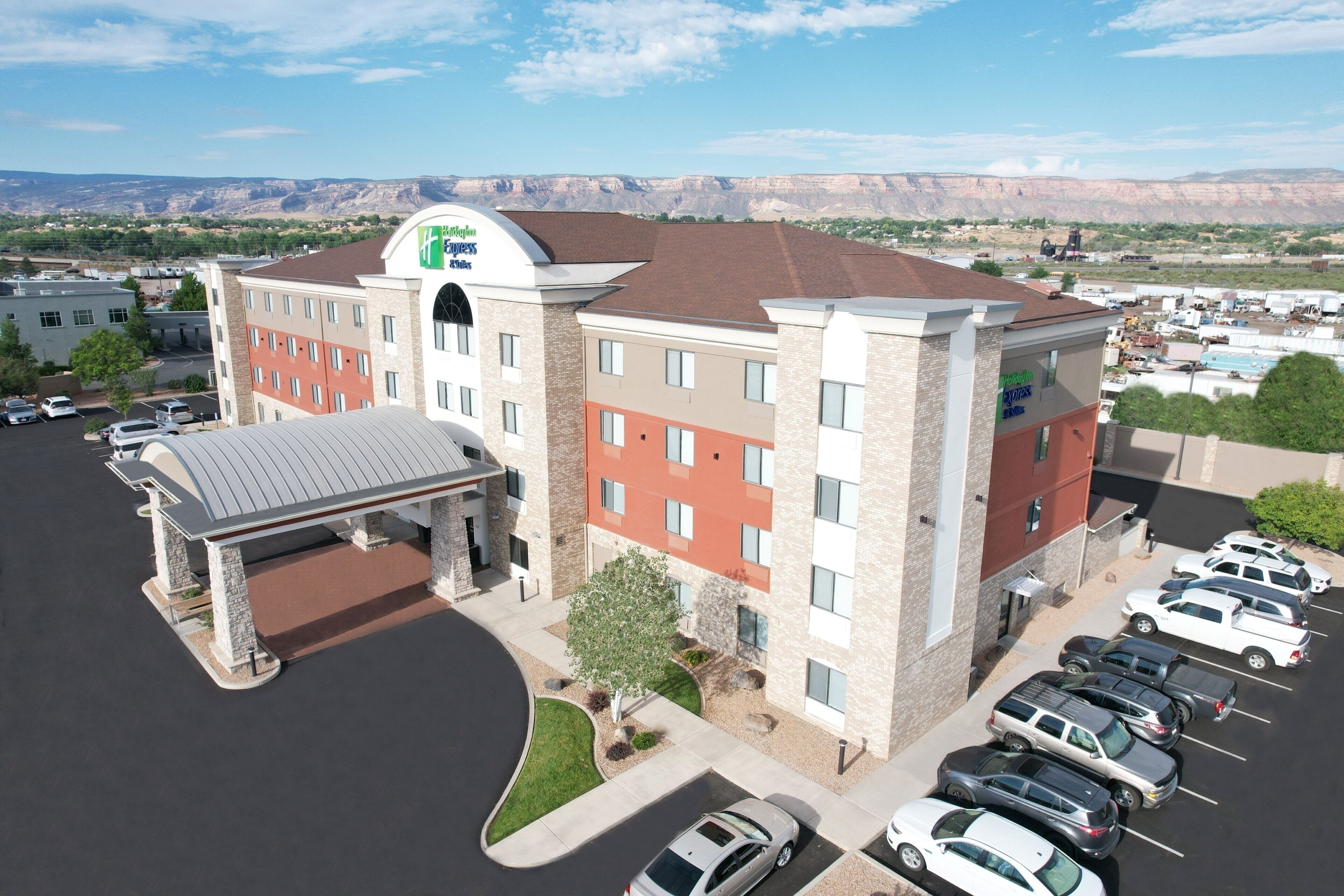 A hotel with a central entrance, multiple parking spaces, and a view of the surrounding landscape.