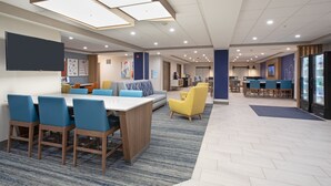 Un moderno vestíbulo de hotel con un área de estar central, un bar y un refrigerador.