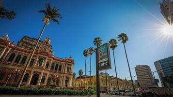 A historic building with classical architecture, palm trees, and a clear sky.