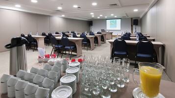 A conference room with tables, chairs, water bottles, and a projector screen displaying "QUALITY HOTEL".