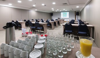 A conference room with tables, chairs, water bottles, and a projector screen displaying "QUALITY HOTEL".