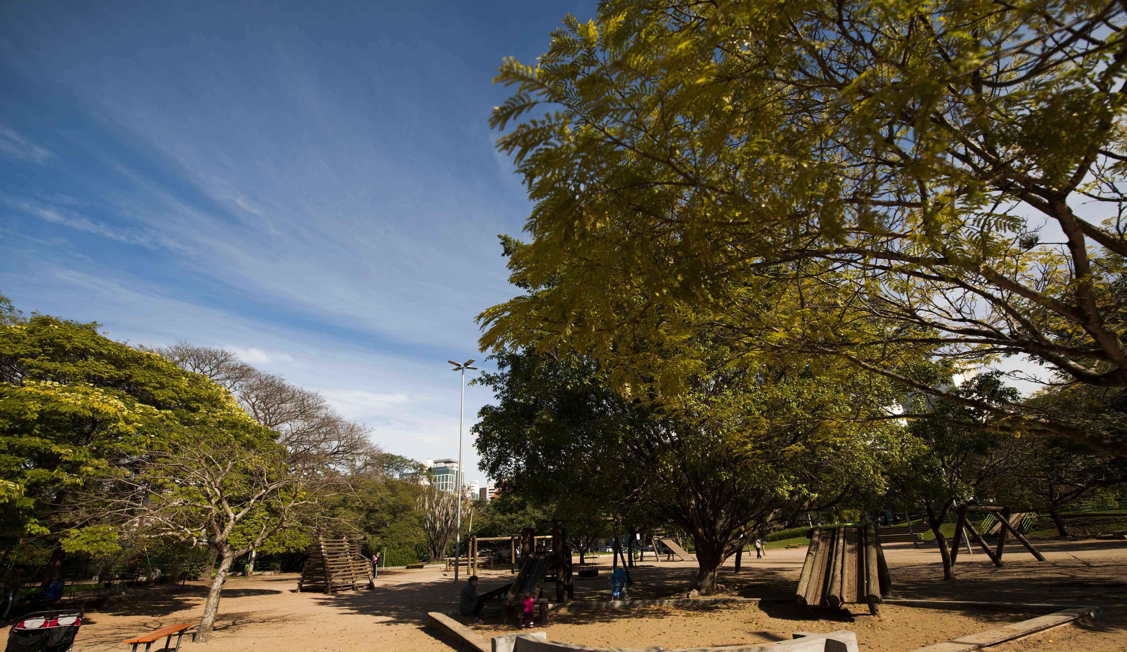 A park with playground equipment, benches, and trees.