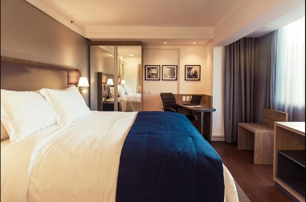 A hotel room with a large bed, a desk, a chair, and a small table. - Slaviero Porto Alegre (Porto Alegre)