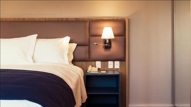 A hotel room with a bed, a nightstand with a lamp, and a phone. - Slaviero Porto Alegre (Porto Alegre)
