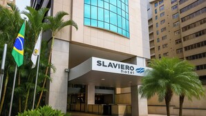The exterior of the Slaviero Hotel with a modern facade, large windows, and palm trees in the foreground. - Slaviero Porto Alegre (Porto Alegre)