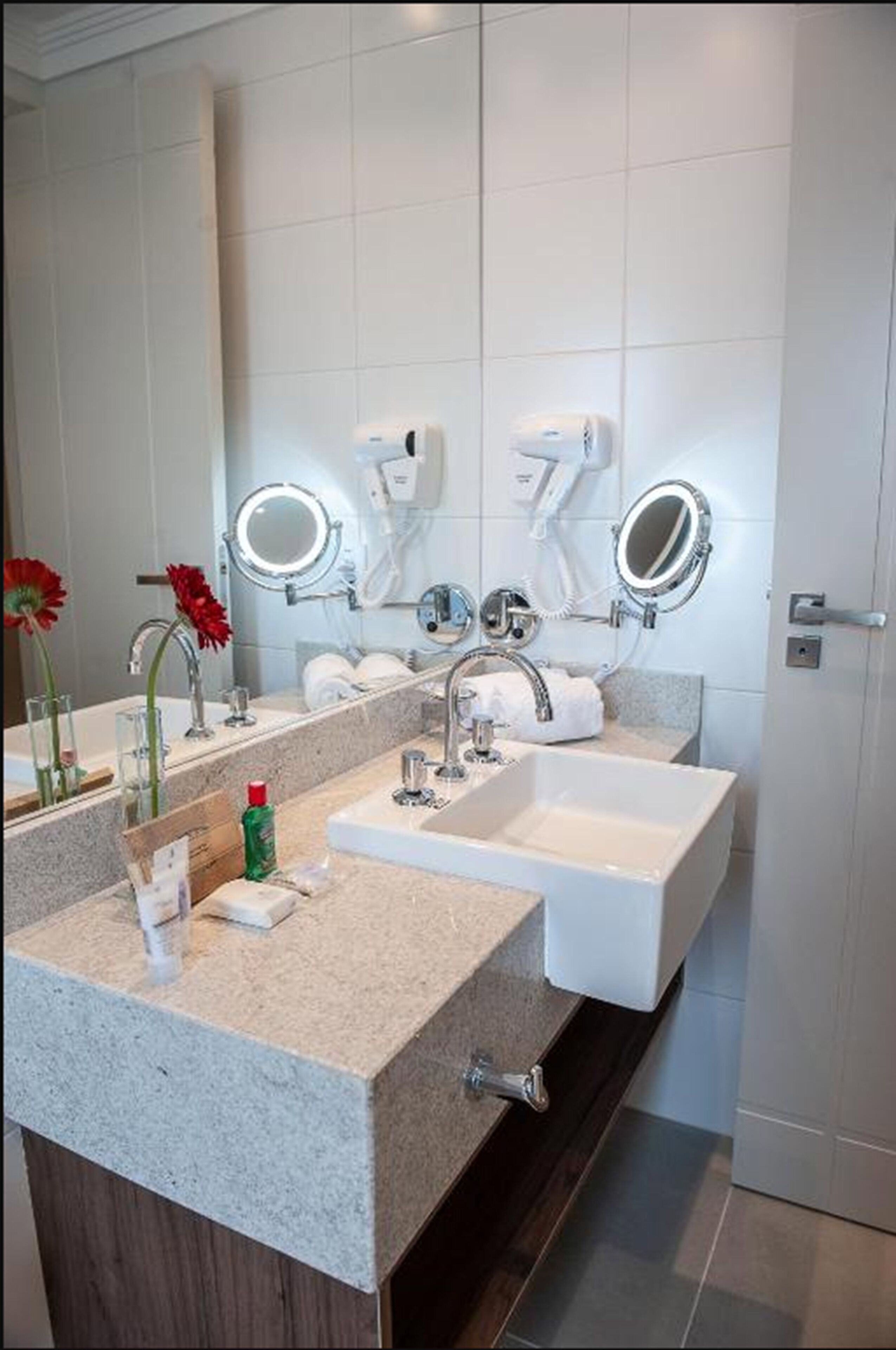 A modern bathroom with two sinks, a large mirror, and a hairdryer.