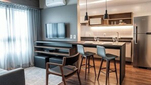 A modern kitchen with a built-in stove, a refrigerator, and a dining area with bar stools. - Slaviero Porto Alegre (Porto Alegre)