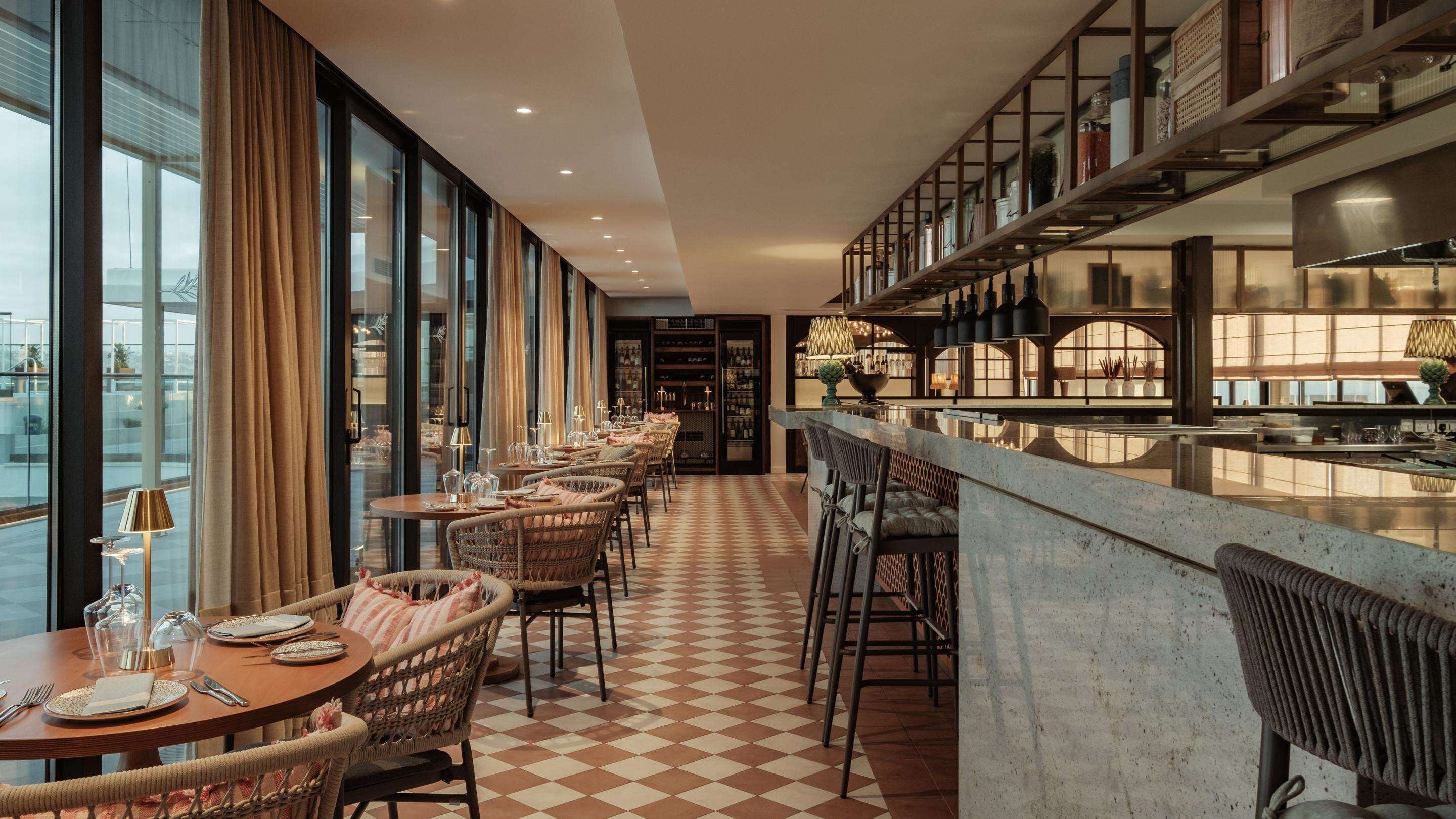 A restaurant with a long dining area, high ceilings, and a checkered floor.