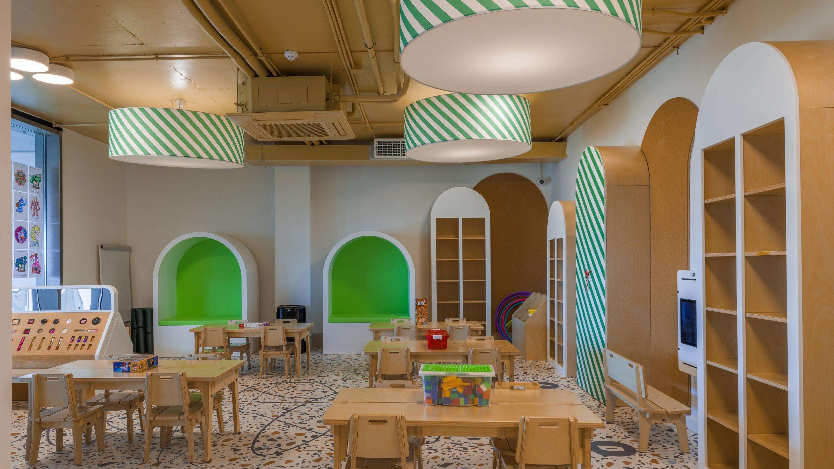 A children's playroom with wooden furniture, green arches, and striped lamps.