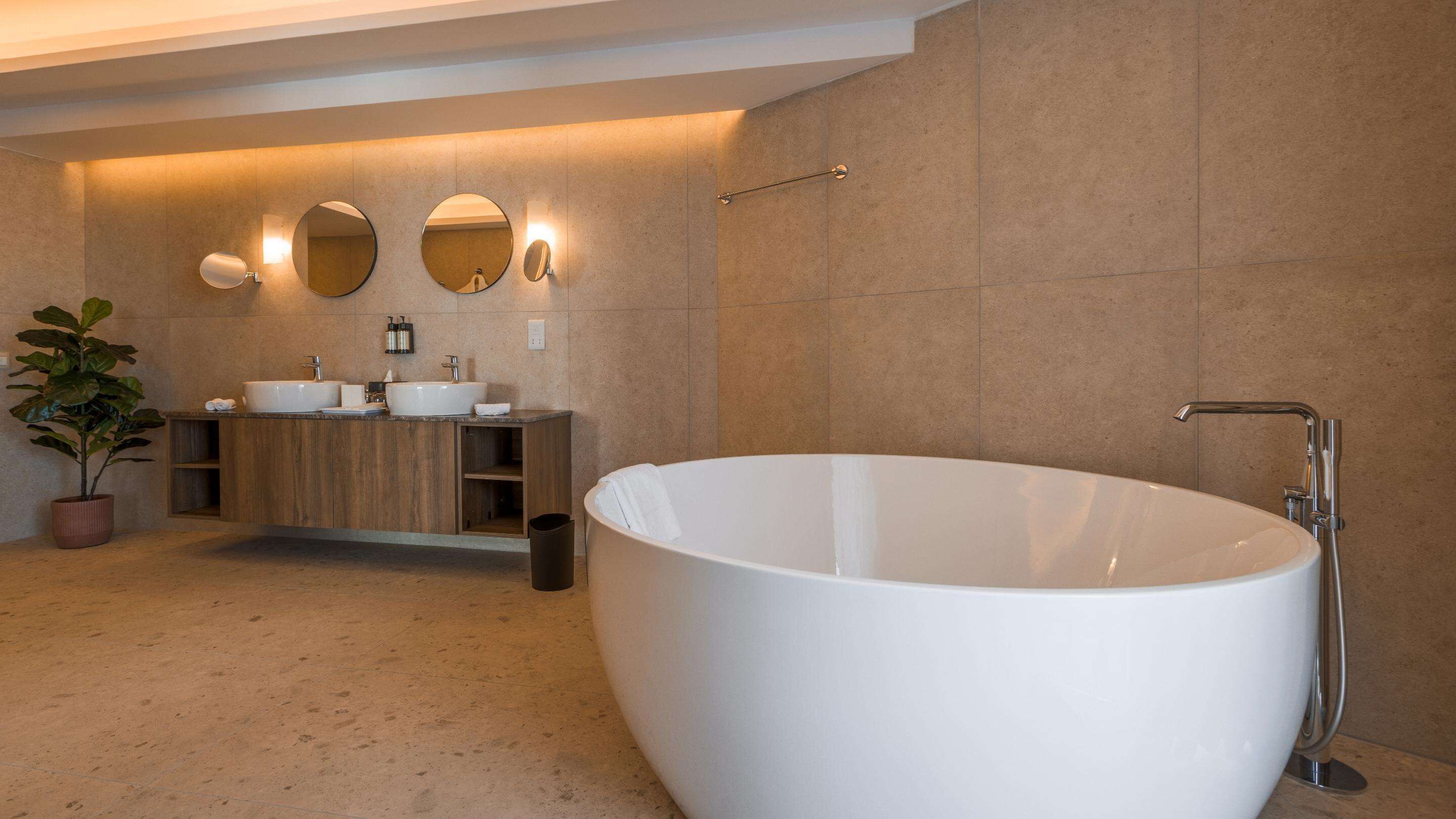 Un baño moderno con una bañera independiente, dos lavamanos y un espejo sobre el mueble de tocador.