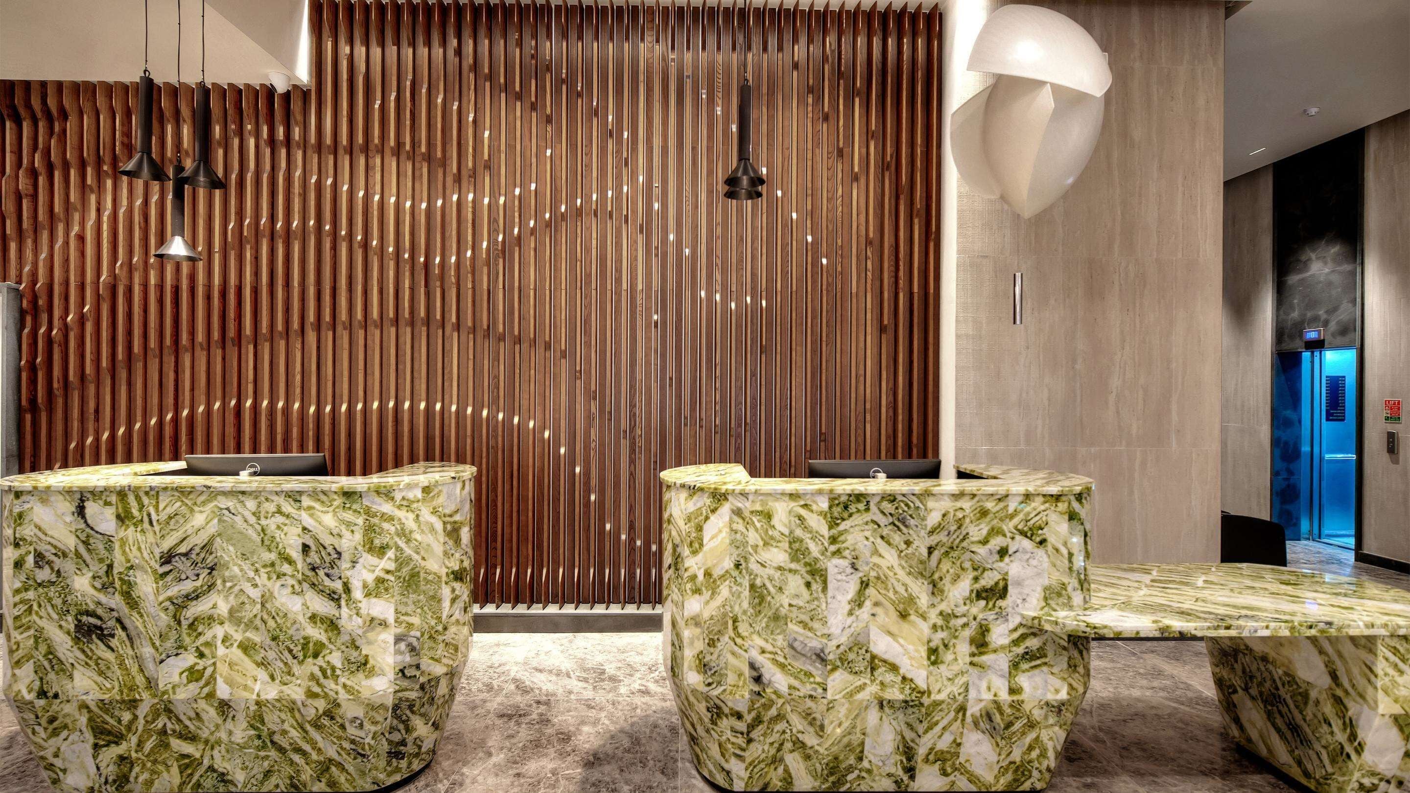 A reception area with marble counters and a wooden slatted wall.