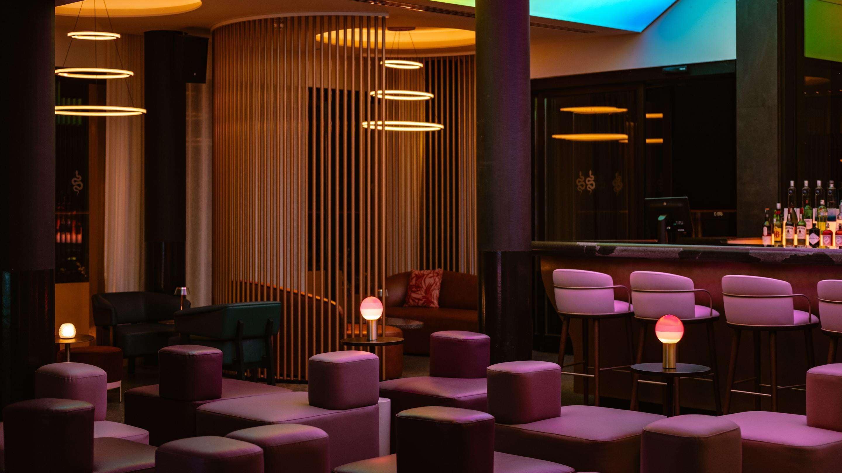 A modern bar area with round tables and purple seating.