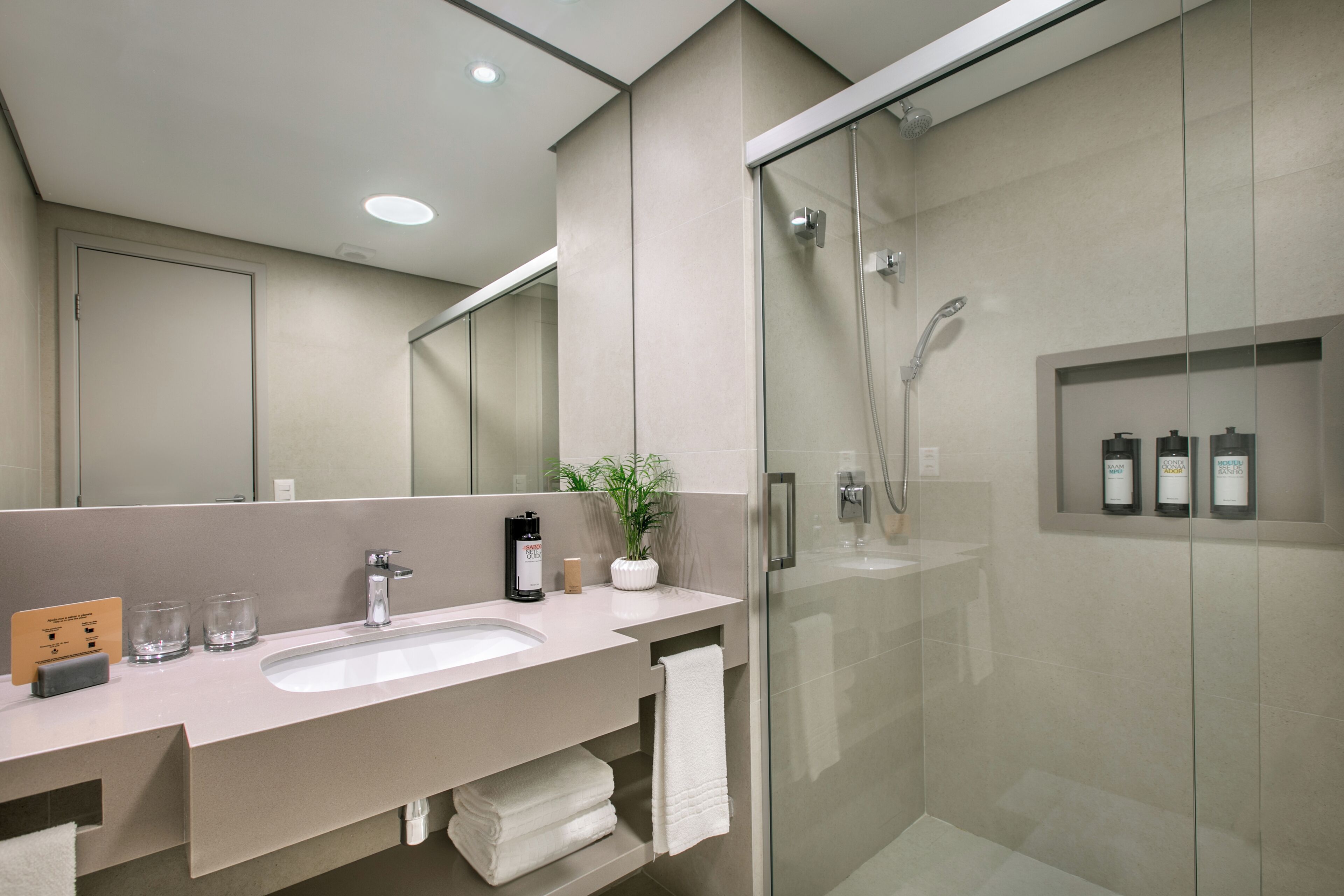 Une salle de bain moderne avec une douche à parois de verre, un grand lavabo et un miroir.