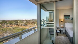 Een balkon met uitzicht op de stad, een bed, een stoel en een klein tafeltje.