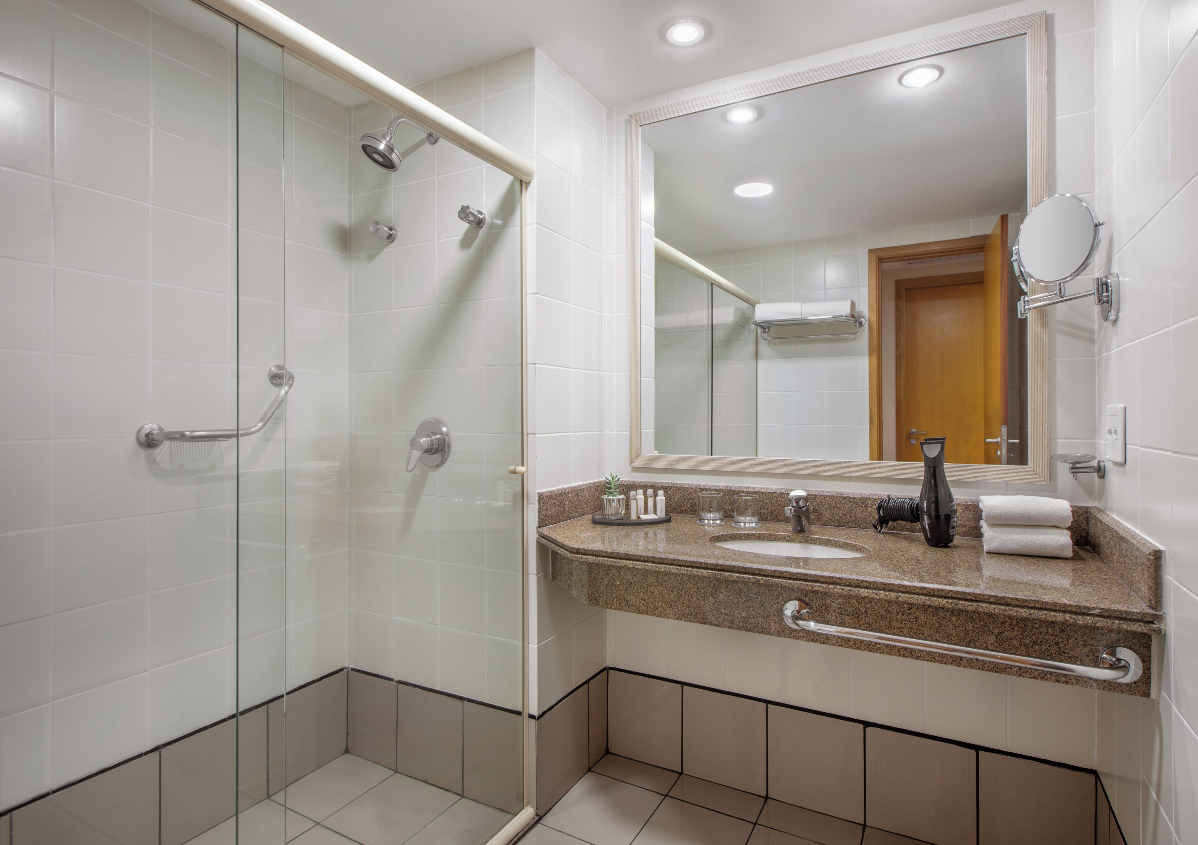 A modern bathroom with a glass shower enclosure, a sink with a vanity, and a large mirror.