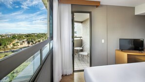 A hotel room with a balcony, a TV, a bed, and a chair.