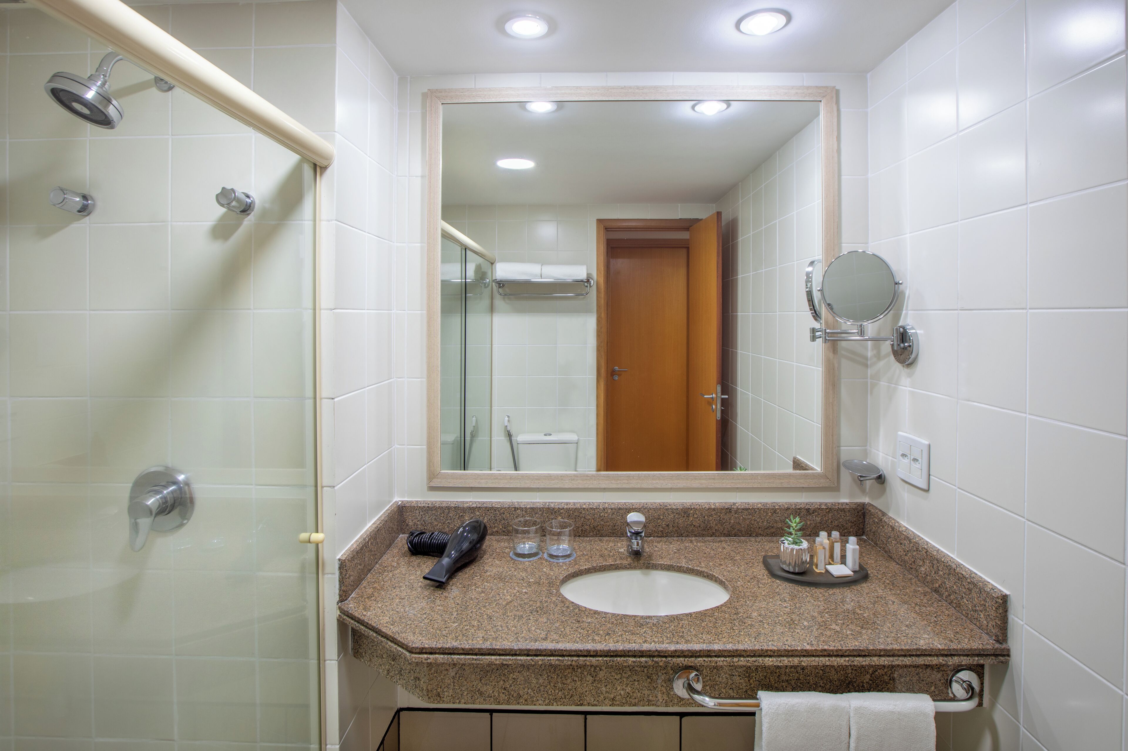 A bathroom with a shower, a sink, a mirror, and a towel rack.