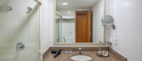 A bathroom with a shower, a sink, a mirror, and a towel rack.