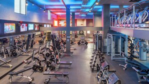 A gym with various exercise equipment, large windows, and a spacious layout.