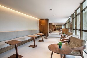 A modern interior with seating areas, wooden tables, and a visible sign with the name 'LUCCA'. - Brasil 21 Suites Affiliated by Melia (Brasília)
