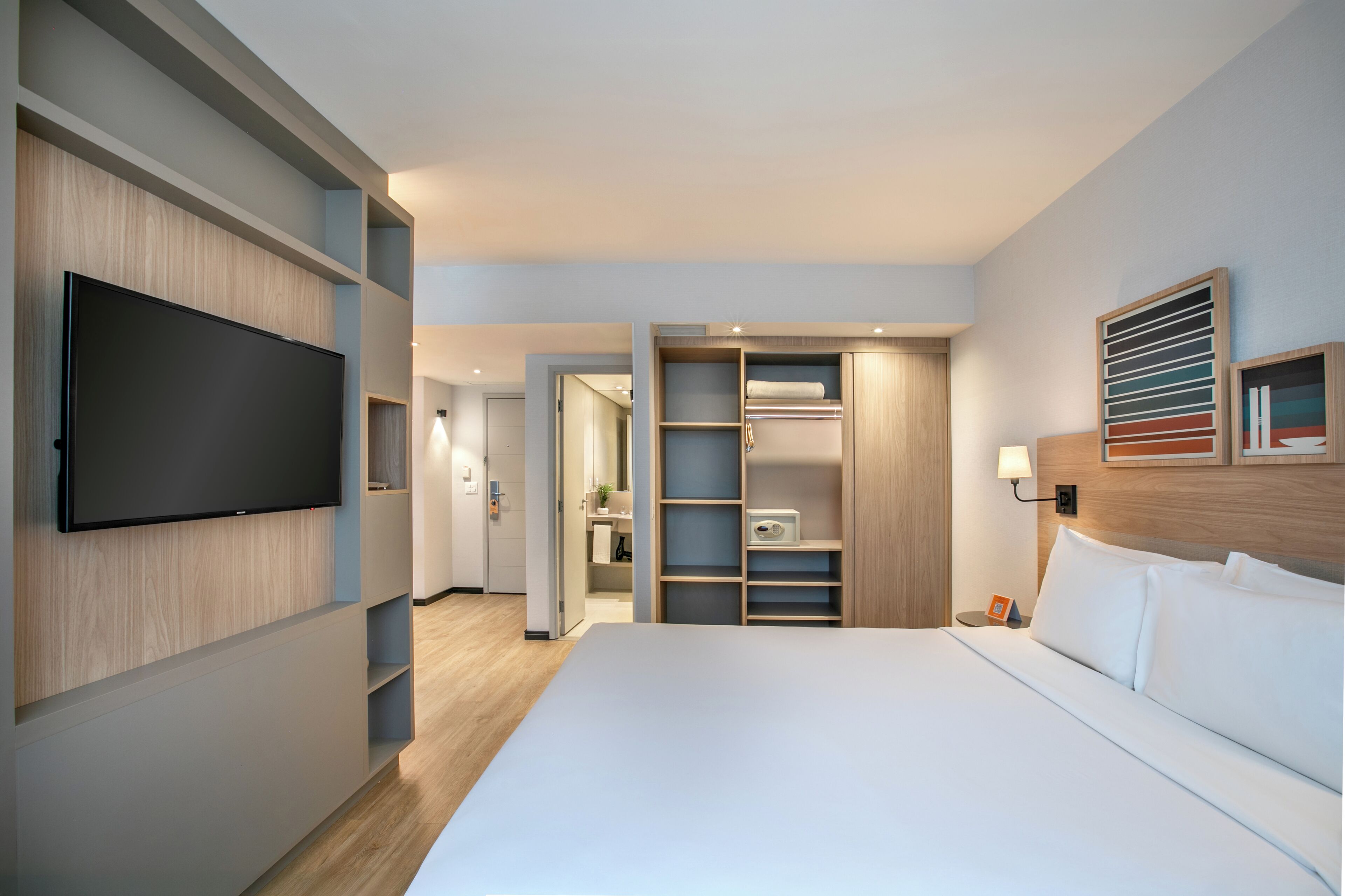 Una habitación de hotel con cama, televisor, vestidor y baño.