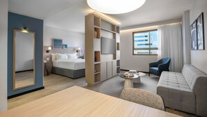 Een moderne hotelkamer met een bed, een sofa, een televisie en een groot raam.