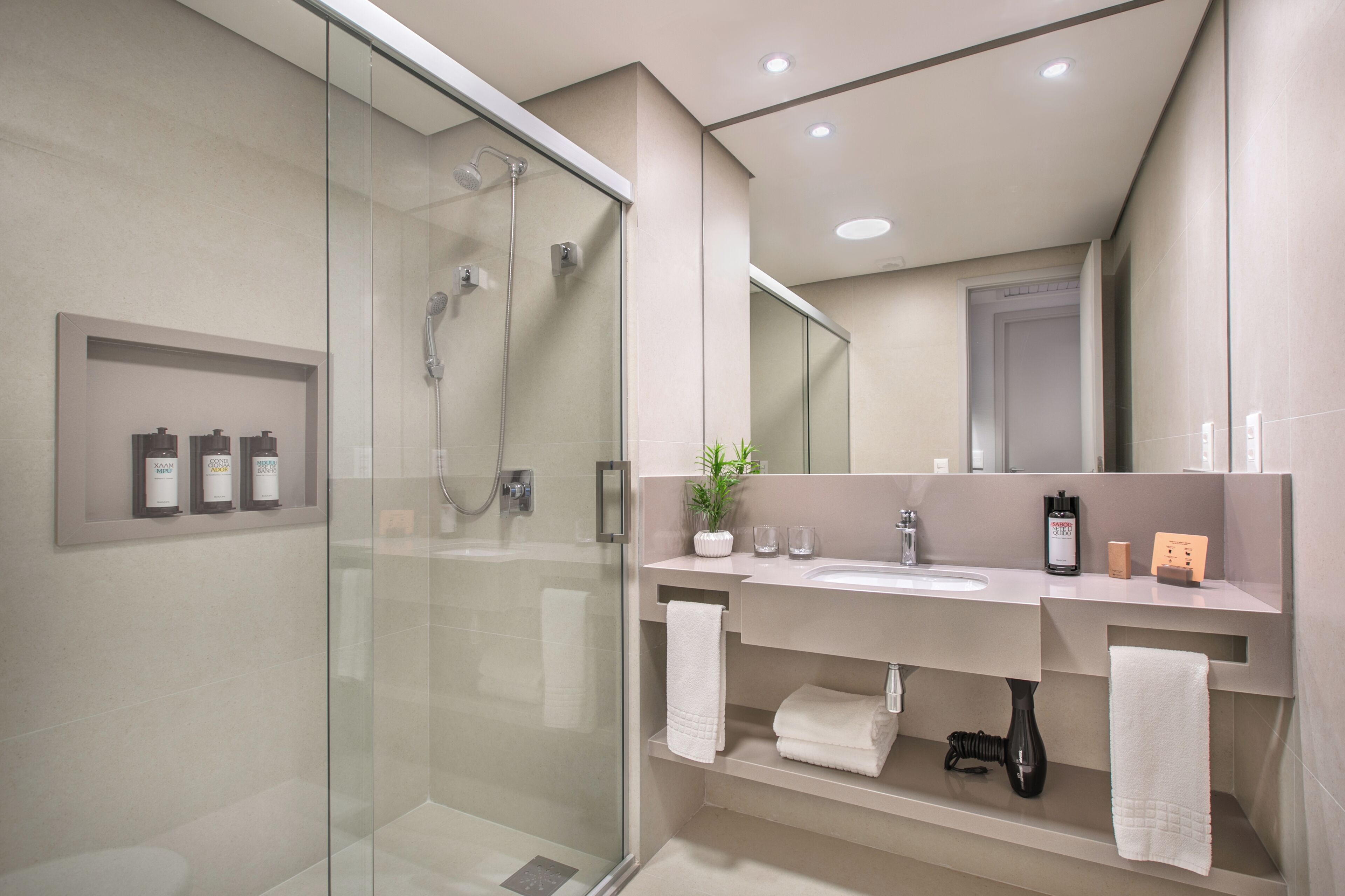 A modern bathroom with a glass-enclosed shower, a vanity with a sink, and a large mirror.